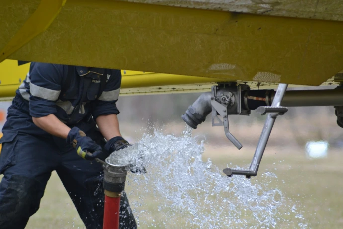 Well Pump Services person in black and yellow wet suit holding black and yellow water hose